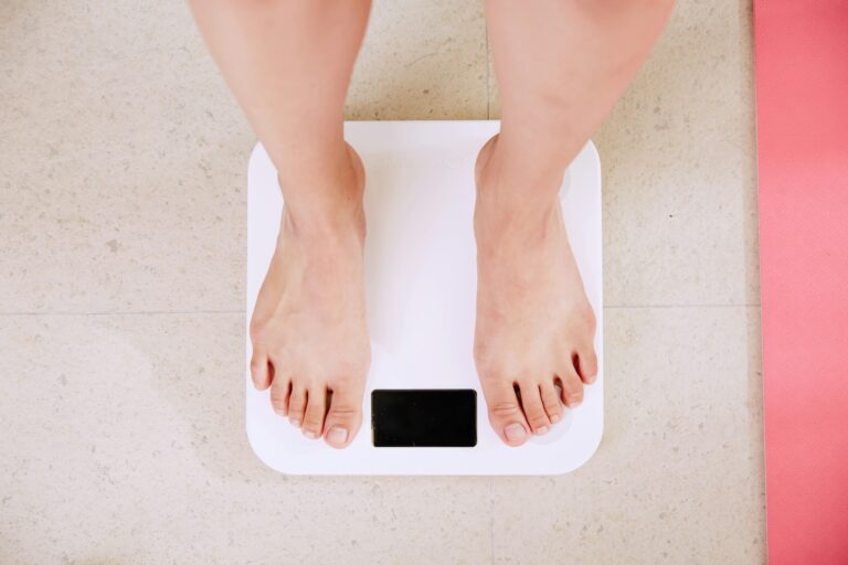 Woman looking frustrated at bathroom scale after strength training with no weight loss