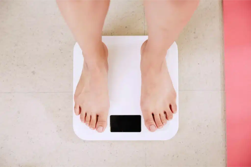 Woman looking frustrated at bathroom scale after strength training with no weight loss